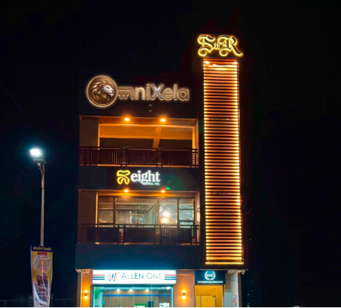 OmniXela building at night with its illuminated gold sign